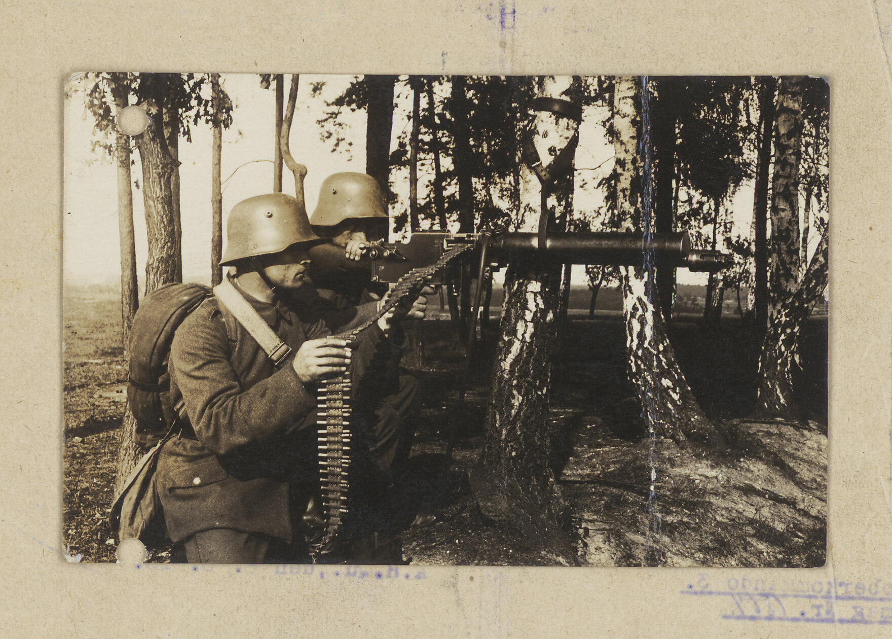 Das Foto zeigt zwei Soldaten an einem Maschinengewehr im Wald.